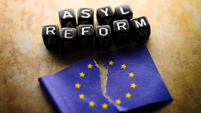 EU-Fahne mit Riss und Schriftzug Asylreform, Symbolfoto EU-Streit und Uneinigkeit