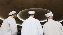 Imame beten mit Gemeindemitgliedern in einer Moschee