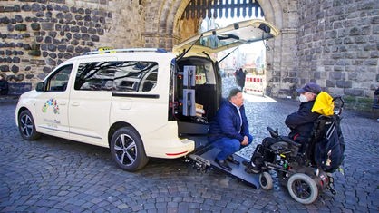 Inklusionstaxifahrer Ibrahim Coban aus Köln transportiert einen Rollstuhlfahrer mit seinem Taxi