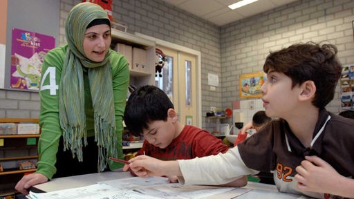 Eine Lehrerin mit Kopftuch unterrichtet zwei Schüler