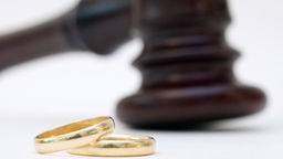 ILLUSTRATION - Zwei goldene Eheringe liegen am 11.12.2012 in Berlin vor einem Gerichtshammer.
