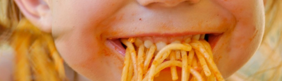 Bambina che mangia spaghetti