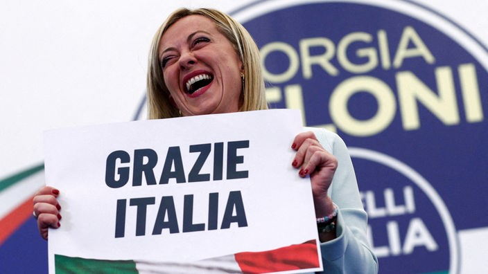 Giorgia Meloni zeigt ein Schild mit darauf "Grazie Italia" geschrieben