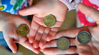 Mani di bambini che mostrano monete da 50 centesimi e due euro