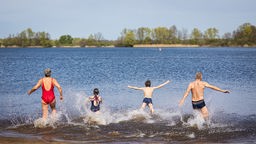 Una famiglia in costume da bagno si butta in un lago