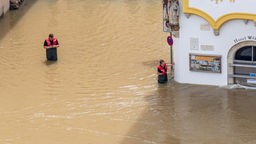 Zwei Menschen laufen im Wasser in der überfluteten Stadt Passau