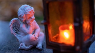 Figurica anđela na groblju gleda u zapaljeni lampion