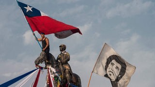 Demonstrant maše čileanskom nacionalnom zastavom pored druge zastave koja prikazuje pokojnog čileanskog glazbenika Victora Jaru tijekom prosvjeda protiv vlade predsjednika Sebastiana Pinere, u Santiagu