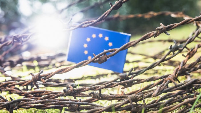 Zastava EU okružena bodljikavom žicom