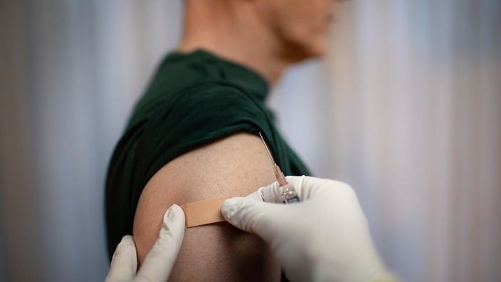 Lekar lepi flaster na rame pacijenta preko mesta na kome mu je upravo dao vakcinu