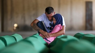 Samed Alić tuguje sa kćerkom pored tabuta s posmrtnim ostacima svog oca, žrtve genocida u Srebrenici, u Potočarima, BiH,