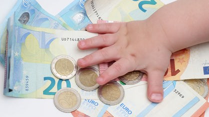 Kinderhand auf Geldscheinen