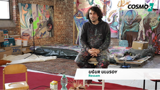 Künstler Ugur Ulusoy Mann sitzt auf Stuhl vor seinen Kunstwerken