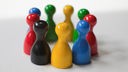 Symbolbild zum Thema gemischte Gruppe - Vielfalt - Integration: Rote, blaue, schwarze, grüne und gelbe Spielfiguren stehen im Kreis zusammen