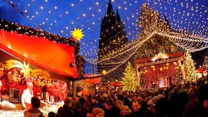 Besucher gehen über den Weihnachtsmarkt vor dem Dom in Köln