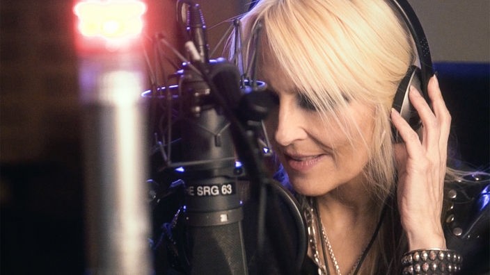 Die Rock-Sängerin Doro Pesch spricht während einer Aufnahme ins Studio-Mikrofon.