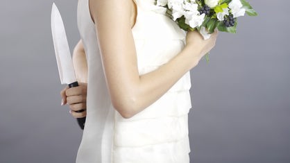 Eine Frau hält einen Blumenstrauß vor sich und ein Messer hinter ihrem Rücken.