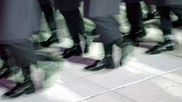 Viele schwarze Stiefel laufen im Gleichschritt.
