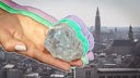 Eine Hand in drei verschiedenen Farben hält einen Diamanten, im Hintergrund die Stadt Antwerpen.