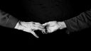Schwarz-weiß: Zwei Hände mit Falten greifen nach einander.