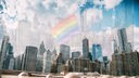 Die Regenbogenflagge wird vor der Skyline New Yorks gespiegelt.