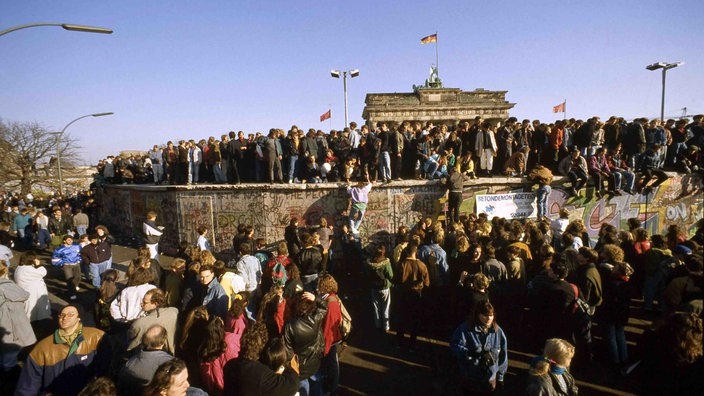 Menschen klettern im November 1989 auf die Mauer in Berlin.