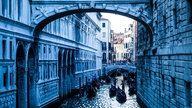 Eine Brücke in Venedig, unter der Gondeln herfahren.