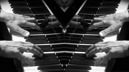 Schwarz-weiß Bild gespiegelt: Hände spielen Klavier.