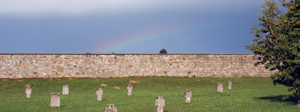 Auf dem ehemaligen Gelände des KZ Mauthausen in Österreich stehen auf einer Wiese Grabsteine zur Erinnerung der Ermordeten.