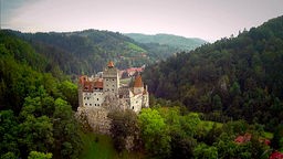 Schloss Bran in Siebenbürgen, mehrere Türme inmitten bewaldeter Hügel