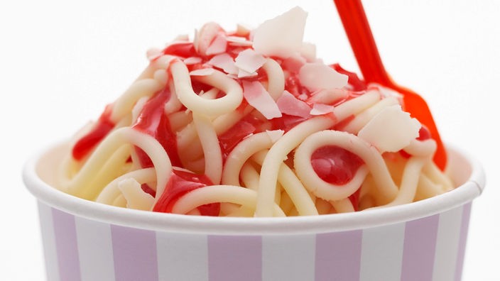 Spaghetti Eis in einem lila-weiß gestreiften Pappbecher.