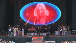 Eine Leinwand zeigt die Sängerin in einem rot-blauen Oval