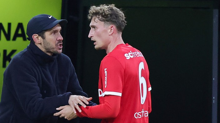 Freiburgs Trainer Julian Schuster (rechts) spricht beschwörend am Spielfeld zu dem abgelämpften Patrick Osterhage