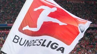 Riesen-Fahne mit Logo (Grafiksymbol: Mann bei Torschuss) und Schriftzug der Bundesliga in einem Stadion (Großaufnahme)