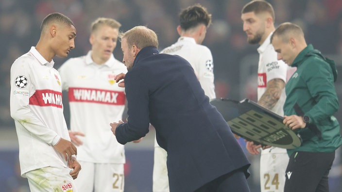 Stuttgarts Enzo Millot (links) am Spielfeldrand im Gespräch mit Trainer Sebastian Hoeneß, im Hintergrund Teamkollegen (unscharf)