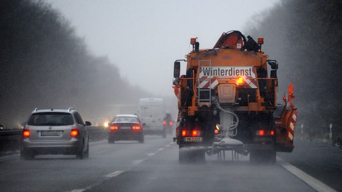 Ein Fahrzeug des Winterdienstes verteilt bei Ratingen im Schneetreiben auf der Autobahn 52 Streusalz.
