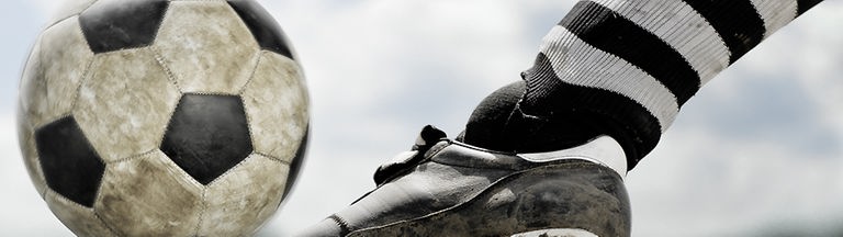 Großaufnahme eines Fußball-Schuhs, der den Ball trifft.