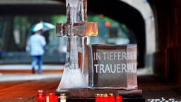 Ein Kreuz und ein quaderförmiger Klotz mit der Aufschrift "In tiefer Trauer" vor dem Tunnel in Duisburg, in dem bei der Massenpanik 21 Menschen starben