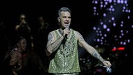 Robbie Williams singt aus voller Kehle und geht dabei über den Steg, der durch das Publikum führt