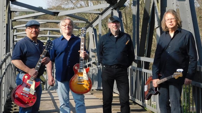 Die vier Mitglieder der Band Bridge Back stehen mit ihren Instrumenten auf einer Brücke.