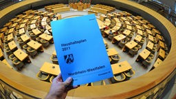 Der gedruckte Haushaltsentwurf 2011 für Nordrhein-Westfalen, der Landtag im Hintergrund