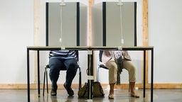 Zwei Bürger wählen hinter einer Wahlkabine