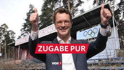 Satirische Fotomontage: Hendrik Wüst steht lachend vor einer maroden und überwucherten Tribüne mit der Aufschrift "Shithole Stadium Gelsenkirchen"