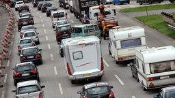PKW und Wohnwagen stehen auf drei Fahrstreifen vor dem Elbtunnel in Hamburg im Stau