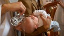 Einem Säugling wird aus einem Gefäß Wasser über den Hinterkopf gegossen