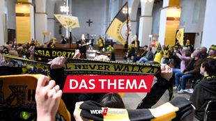 Fans halten beim Gottesdienst in der Gründungskirche des BVB ihre Fanschals in die Höhe (26.05.2023)