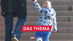 Ein Mann geht mit einem Kind an der Hand eine Treppe hinauf