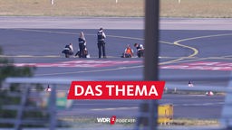 Flughafen Düsseldorf: Polizisten stehen auf dem Flugfeld und versuchen Aktivisten der Gruppe "Letzte Generation", die sich dort festgeklebt haben, vom Asphalt zu lösen.
