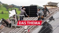 Handwerker montieren Solarpanels auf einem Hausdach