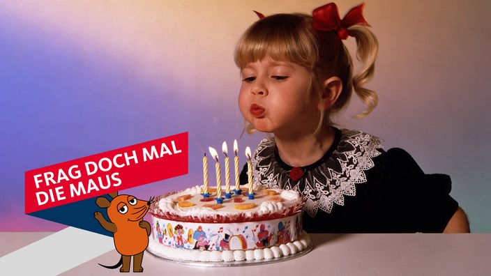 Ein Mädchen bläst Kerzen auf einem Geburtstagskuchen aus